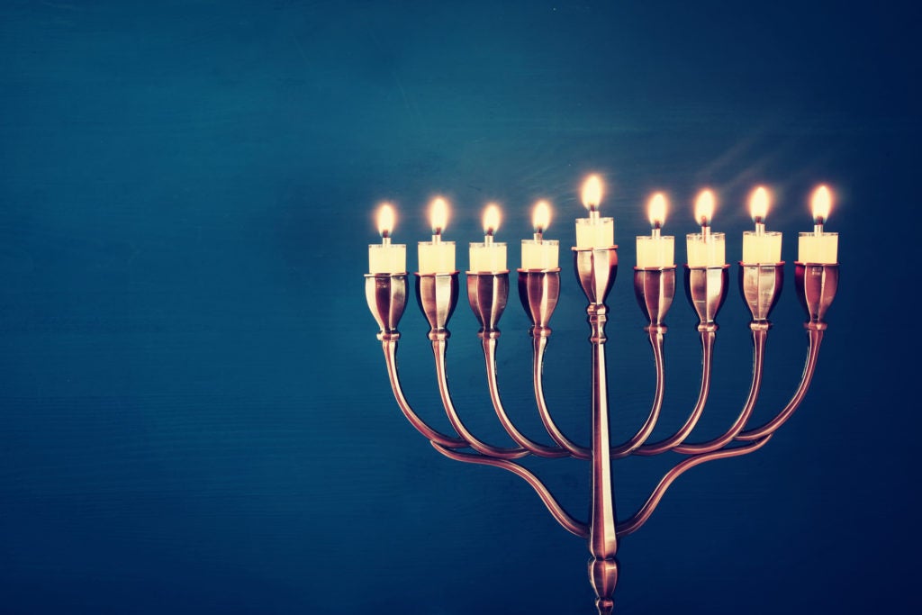 Image of jewish holiday Hanukkah background with menorah (traditional candelabra) and burning candles