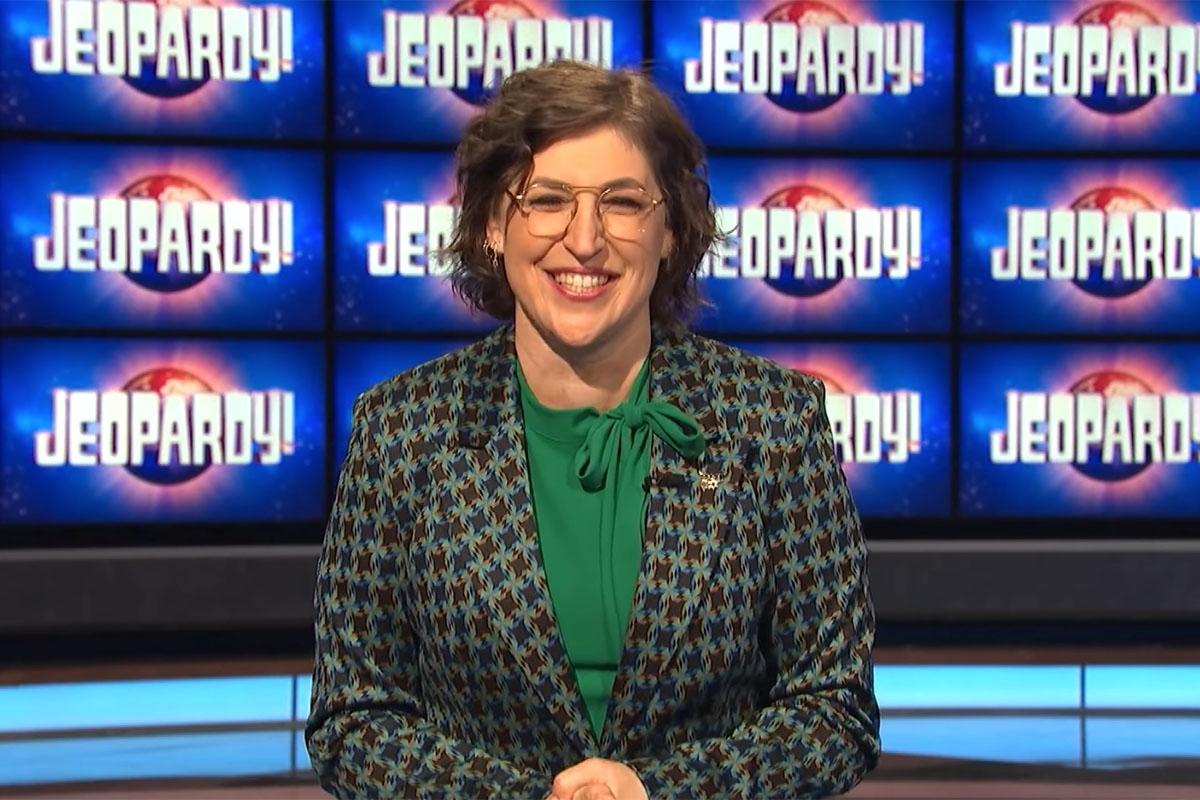 Mayim Bialik in front of "Jeopardy" background.