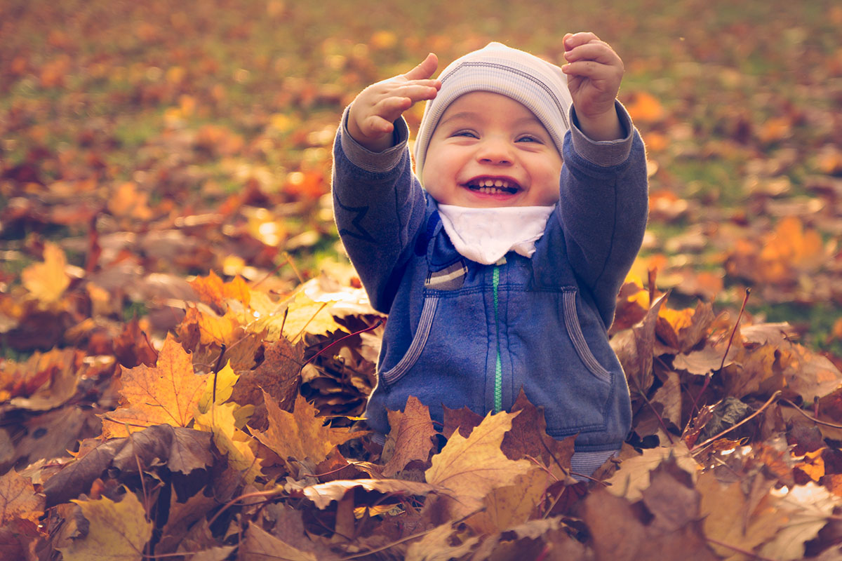 happy baby playing in fall leaves