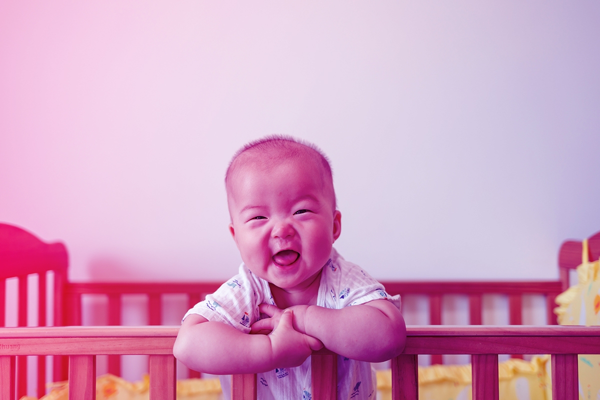 Asian Baby Girl Standing In Crib Laughing