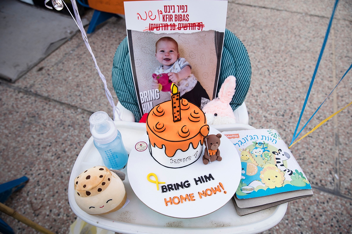 TEL AVIV, ISRAEL - JANUARY 18: A birthday cake is set on a baby chair with a photo of Kfir Bibas, who is held hostage in the Gaza Strip by Hamas, during an event to mark his first birthday on January 18, 2024 in Tel Aviv, Israel. More than 100 Israeli hostages, who were taken captive by Palestinian militants during the Oct. 7 attacks, remain in captivity in Gaza, according to Israeli authorities. Earlier this week, a deal was struck to allow medicine to be brought to the hostages, in exchange for Israel allowing more humanitarian aid to be permitted into Gaza. (Photo by Amir Levy/Getty Images)