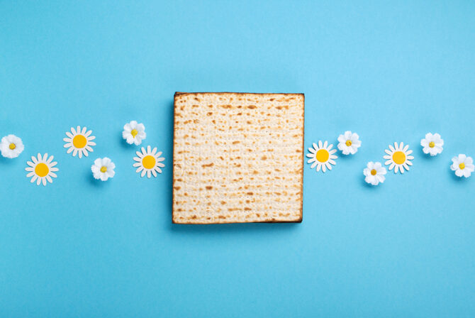 Passover Greeting Card with Matzah, Nuts and Spring Flowers on Blue Background.