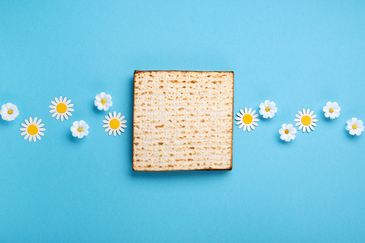 Passover Greeting Card with Matzah, Nuts and Spring Flowers on Blue Background.