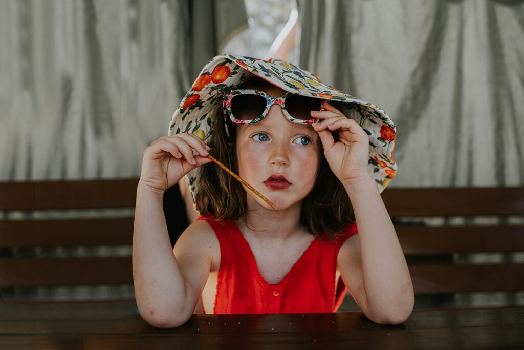 Portrait of a little girl wearing a sunhat and sunglasses and sweating