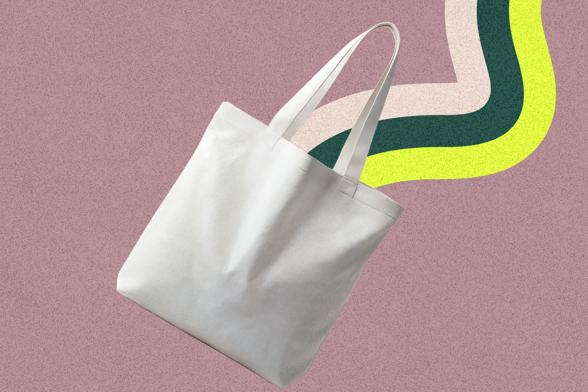 A tan canvas tote bag floating on a rainbow background.