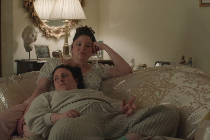 Lena Dunham as Nora in "Too Much" lying on the lap of star Meghan Stalter, who plays her sister Jessica, in the home of their Jewish grandmother Dottie (Rhea Perlman)