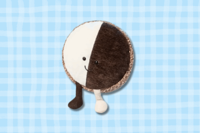 a photo of a plush toy shaped like a black and white cookie, on a blue background