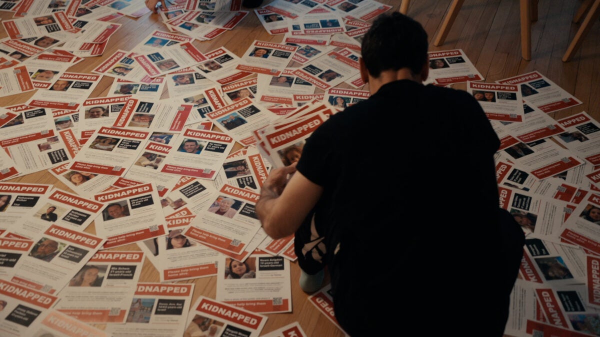 a person looks over hundreds of hostage posters on the floor