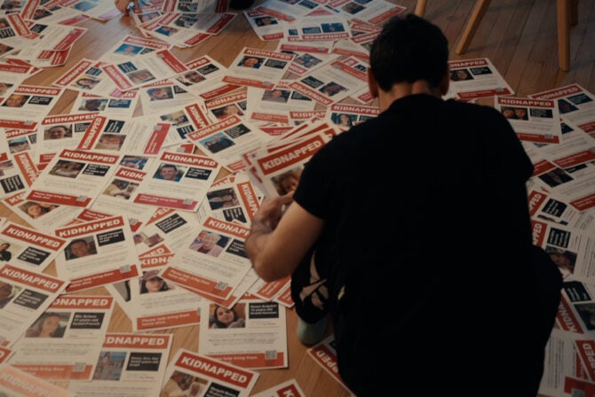 a person looks over hundreds of hostage posters on the floor