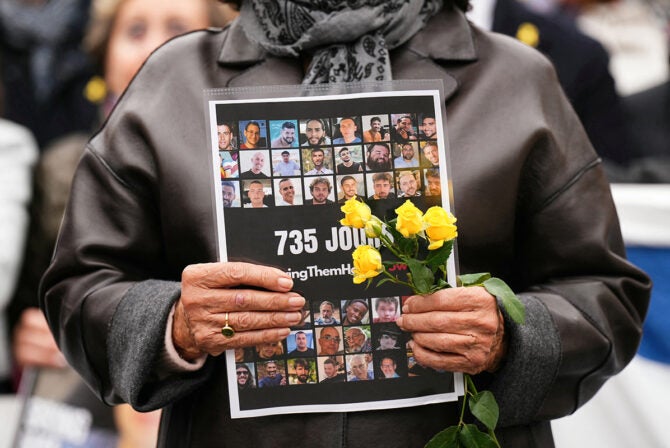 A woman holds a placards bearing the portraits of held hostages during a rally asking for the release of the hostages taken during Hamas's October 7, 2023 attack, at the Trocadero esplanade also called the Parvis des Droits de l'Homme, in central Paris, on October 10, 2025, after Israel and Hamas agreed a Gaza ceasefire deal. Israeli Prime Minister's office said on October 10 that the government had "approved the framework" of a hostage release deal with Hamas, as both sides edged closer to ending more than two years of hostilities in Gaza. The Gaza deal follows a 20-point peace plan for Gaza announced last month by US President Donald Trump, who said he planned to leave on October 12 for the Middle East. (Photo by Dimitar DILKOFF / AFP)